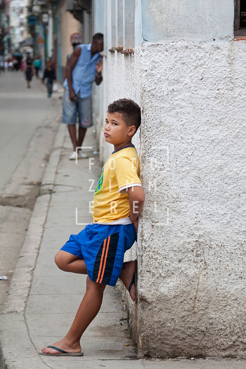 boy leaning back at a wall in the street of havannain havanna